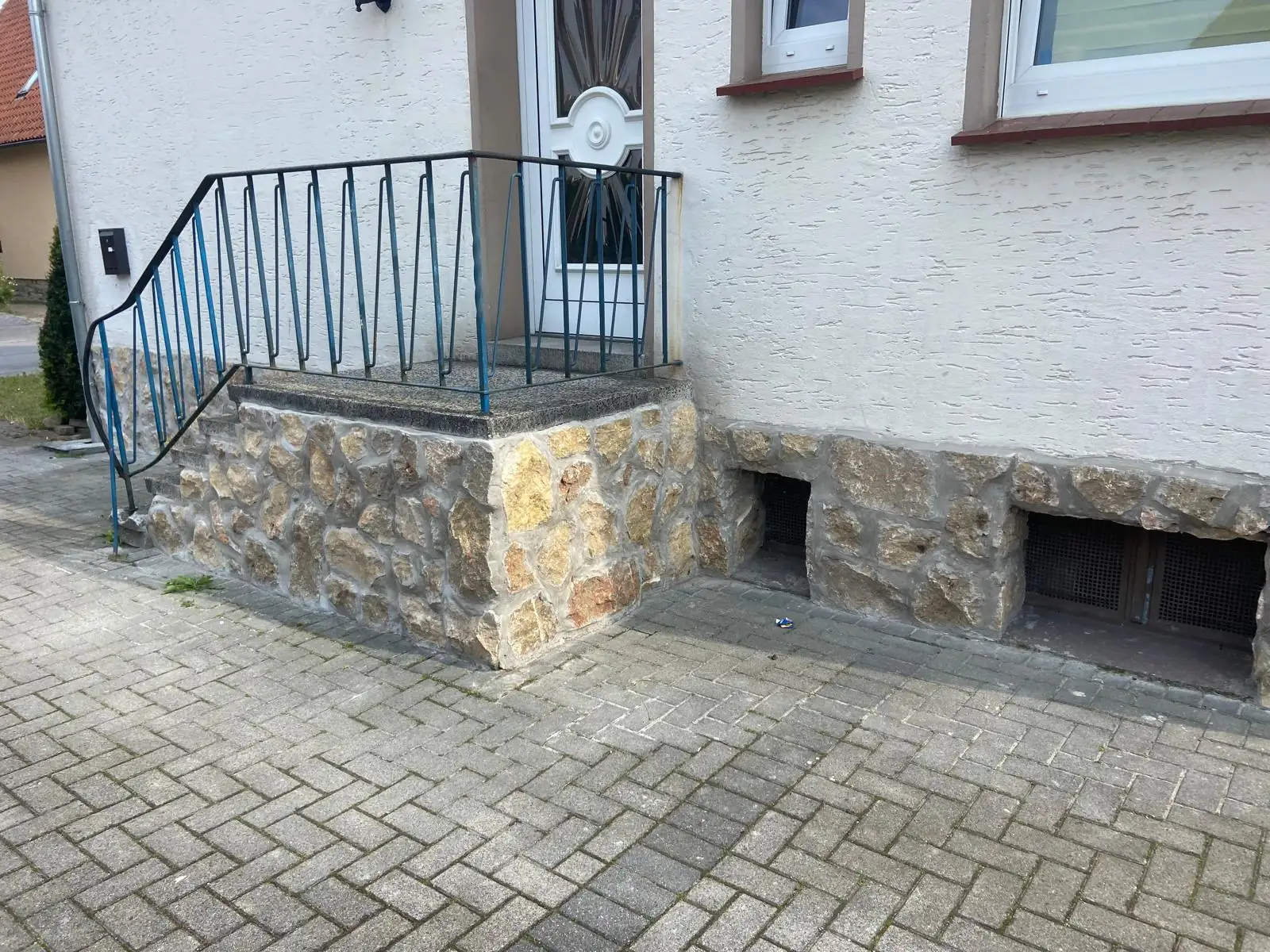 Naturstein-Sockel am Eingangsbereich mit Pflasterfläche